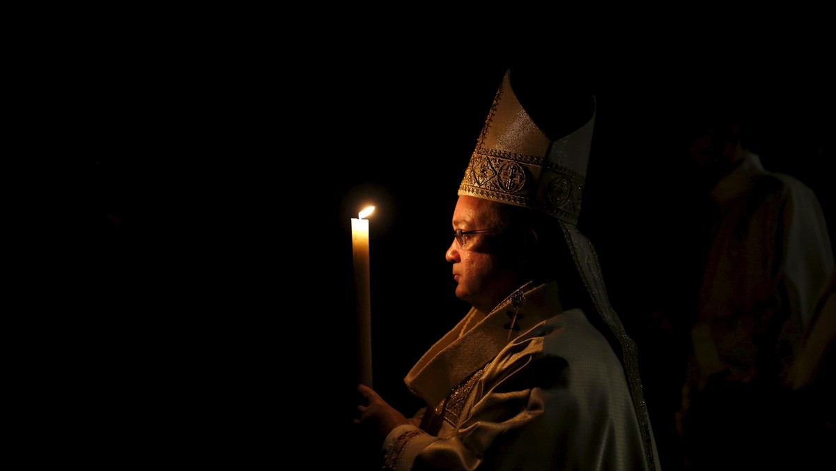 The Archbishop of Malta, Charles Scicluna, carries a candle at the start of an Easter vigil mass at St John's Co-Cathedral in Valletta