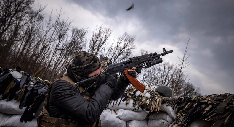 A Ukrainian serviceman shoots at a Russian drone from a trench at the front line east of Kharkiv, March 31, 2022.