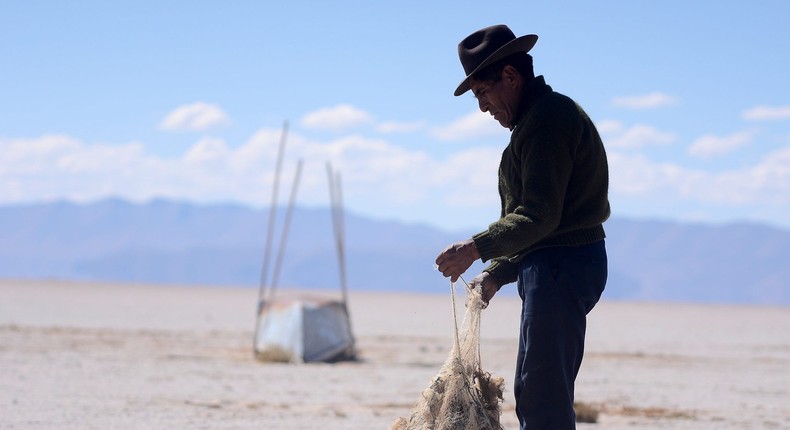 Valerio Rojas picking up an old fishing net in Lake Poop, Bolivia's second-largest lake, which has dried up because of water diversion for irrigation and a warmer, drier climate, on July 24, 2021.