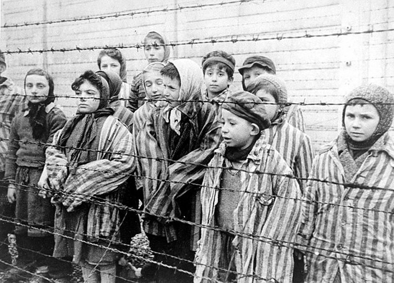 Dzieci za drutami obozu. Zdjęcie stanowi kadr z sowieckiego filmu dokumentującego wyzwolenie Auschwitz