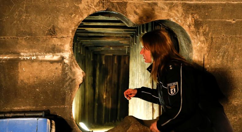 A German police officer looks through the entrance of a tunnel January 17, 2013, dug by thieves in order to enter the safe deposit room of a bank in Berlin. Robbers dug the 100-foot (30 metre) long tunnel, from a nearby underground parking garage into a branch of Berliner Volksbank and stole the contents of several hundred safe-deposit boxes.