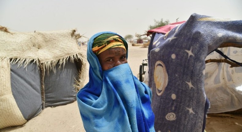 A girl hides herself next to a makeshift tent in a camp in the village of Kidjendi near Diffa, Niger on June 19, 2016 as displaced families fled from Boko Haram attacks in Bosso