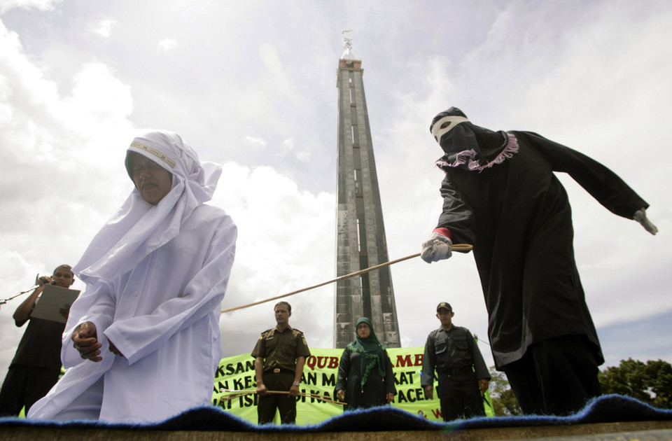 Murni Amris, an Acehnese woman, is caned as part of her sentence in the courtyard of a mosque in Aceh Besar district, Indonesia's Aceh province October 1, 2010.