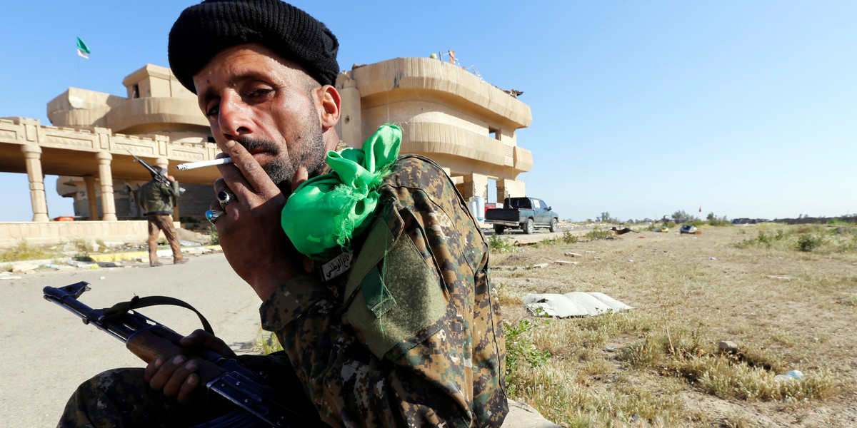 A Shiite fighter from Hashid Shaabi (Popular Mobilization) smokes next to former Iraqi President Saddam Hussein's palace in the Iraqi town of Ouja, near Tikrit, March 17, 2015.
