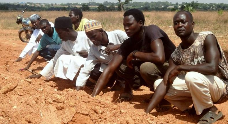 Members of the Islamic Movement of Nigeria, a Shiite group, pray at a mass grave in which 300 members of the organisation are said to be buried