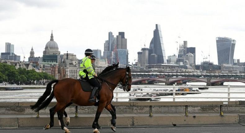 Police on horses ride past a security barrier between the road and the pavement on Waterloo Bridge in London on June 5, 2017, installed in reaction to the recent terror attacks
