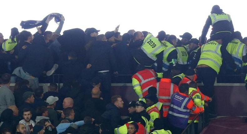 Police and stewards try to separate supporters of West Ham United and Chelsea as they confront each other during the English League Cup match at London Stadium on October 26, 2016