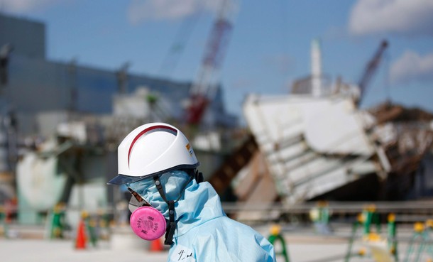 A Tokyo Electric Power Co. employee, wearing a protective suit and a mask, walks in front of the No.