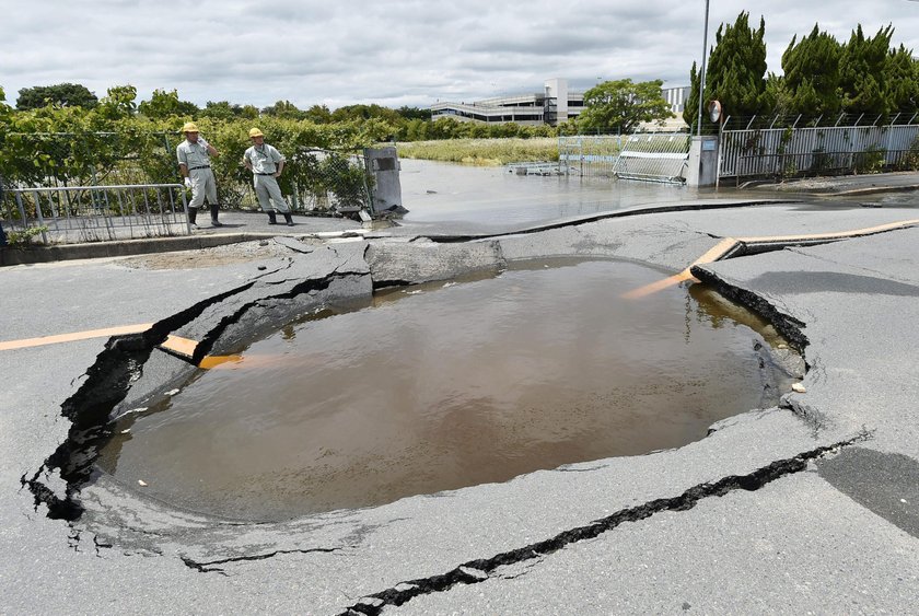 Employees try to remove bottles and cans of beverages which are scattered by an earthquake at a liqu