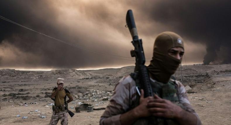 Iraqi soldiers look on as smoke rises from the Qayyarah area, some 60 kilometres (35 miles) south of Mosul