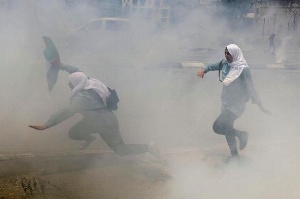 Palestinian school girls run for cover from tear gas fired by Israeli troops during clashes at a pro