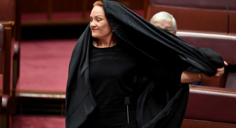 Australian One Nation party leader, Senator Pauline Hanson pulls off a burqa in the Senate chamber at Parliament House in Canberra, Australia, August 17, 2017. 