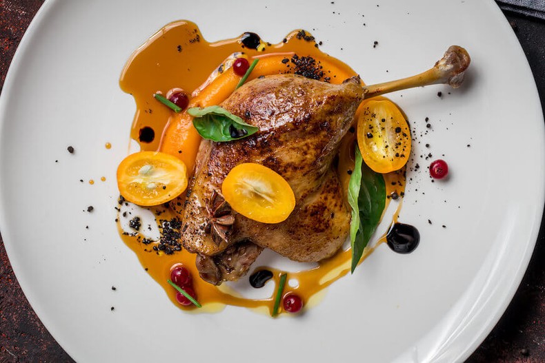 Duck leg Confit on a white plate covered in a sauce is an example of haute cuisine [Escoffieronline]