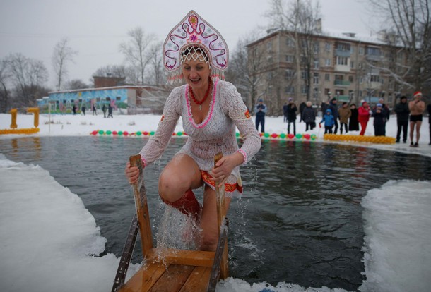 A participant wearing Kokoshnik, the Russian traditional headwear, walks out of the water during win