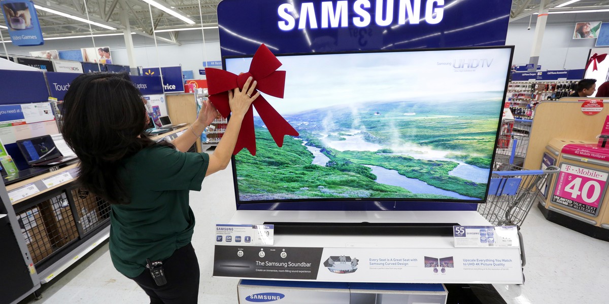 An employee adjusting a large ribbon on a television display at Walmart in preparation for Black Friday in Los Angeles in 2014.