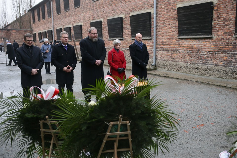 Złożenie kwiatów i zapalenie zniczy przed Ścianą Śmierci na terenie byłego niemieckiego nazistowskiego obozu koncentracyjnego i zagłady Auschwitz-Birkenau w Oświęcimiu