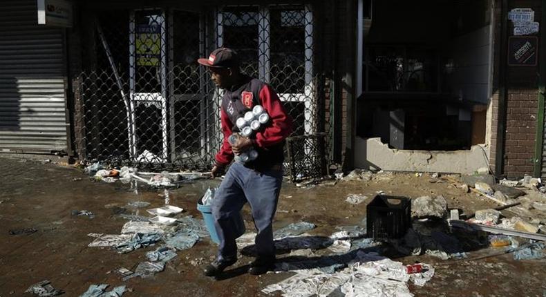 A looter makes off with goods from a store in Germiston, east of Johannesburg, South Africa [Themba Hadebe/The Associated Press]