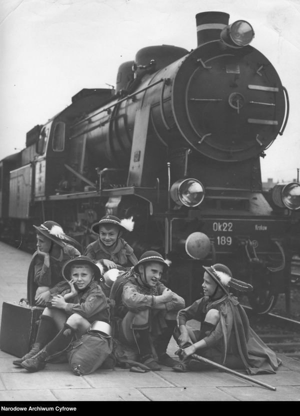 Grupa zuchów z bagażami na peronie dworca przy parowozie Ok 22 nr 189, 1939 rok (Narodowe Archiwum Cyfrowe, domena publiczna)