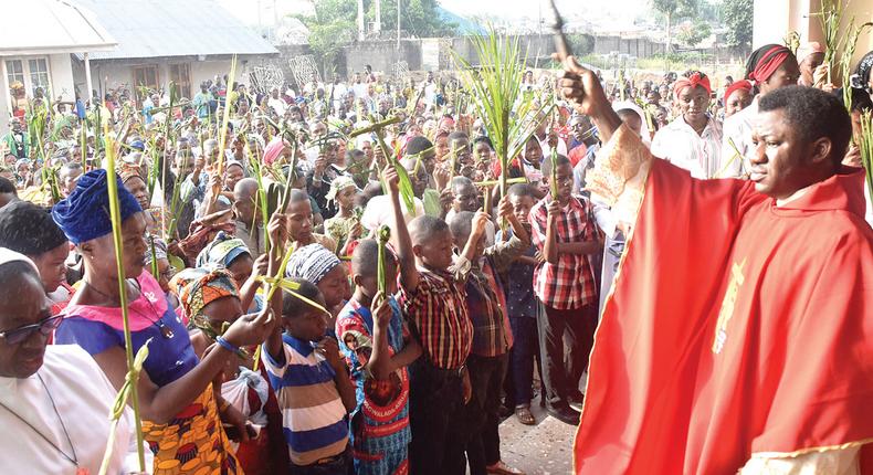 Rev. Fr. Henry Kwasu (right), blessing Catholic faithful and their palms, during the Palm Sunday at the Sacred Heart Catholic Church, Gwagwalada in Abuja… yesterday. PHOTO: NAN