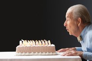 Senior Hispanic man blowing out birthday candles