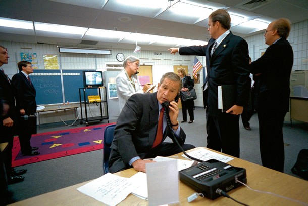 Prezydent George W. Bush zbiera informacje o ataku terrorystycznym w Szkole Podstawowej im. Emmy E. Booker w Sarasocie na Florydzie, w tle na ekranie telewizora transmisja z ataku na WTC, 11 września 2001 r.