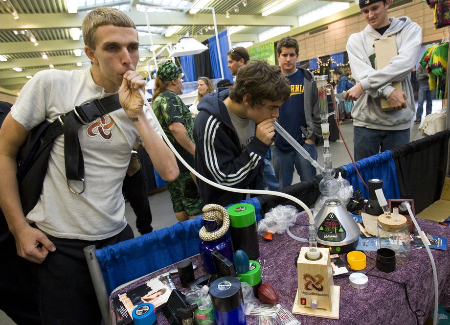 Young men smoke from a vapor pipe, left, and a water pipe at the The Wonders of Cannabis Festival in San Francisco, California.