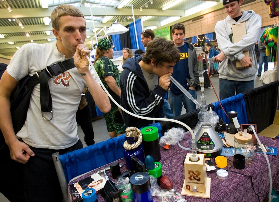 Young men smoke from a vapor pipe, left, and a water pipe at the The Wonders of Cannabis Festival in San Francisco, California.