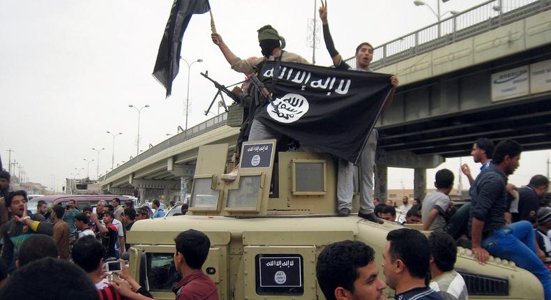 A March 30, 2014 file photo shows Islamic State militants raising their flag atop a commandeered Iraqi military vehicle in Fallujah, Iraq.File/AP