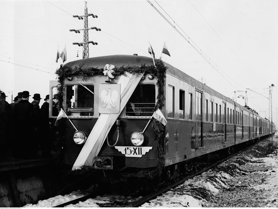 15 grudnia 1936 roku otwarto zelektryfikowaną linię kolejową, łączącą Warszawę z Pruszkowem i Otwockiem. Na pierwszym planie pierwszy pociąg elektryczny E-91