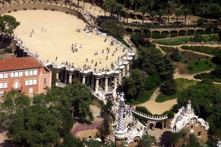<strong>Park Güell</strong>
<br></br>
Park Güell to duży ogród z elementami architektonicznymi zaprojektowany przez katalońskiego architekta Antonio Gaudíego na życzenie jego przyjaciela Eusebi Güella, przemysłowca barcelońskiego, który – zauroczony angielskimi „miastami-ogrodami” – przedsięwzięcie sfinansował. Projekt w założeniu miał być osiedlem dla bogatej burżuazji. Prace trwały w latach 1900-1914. Projektu tego Gaudí nigdy nie ukończył. Powstało jedynie pięć budynków: dwa pawilony po dwóch stronach głównego wejścia oraz trzy inne w samym parku. W jednym z nich od roku 1906 mieszkał sam Gaudí. W 1922 roku władze Barcelony wykupiły teren i przekształciły go w park miejski.
<br></br>
Park jest otoczony murem, zbudowanym z kamieni o nieregularnym kształcie. Znajduje się w nim siedem bram. Nad główną bramą znajdują się dwa medaliony ze słowami „Park” i „Güell”, ułożonymi za pomocą mozaiki trencadis – kawałków potłuczonych, ceramicznych płytek. Park składa się z wielu fragmentów zieleni, pociętych systemami krętych ścieżek, mostków i ciągami schodów.
<br></br>
Fot. Amadalvarez / Wikimedia Commons / CC-BY-SA