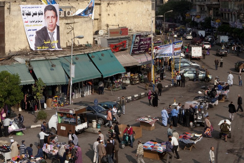 Handel uliczny w Kairze: sprzedawcy zgromadzeni pod plakatem wyborczym, Egipt, listopad 2011