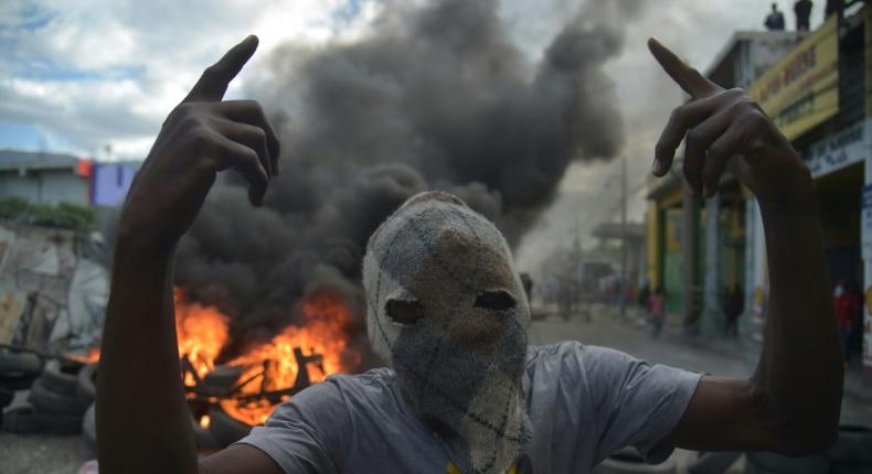 A masked demonstrator gestures before burning tires during protests in Port-au-Prince, on February 10, 2019