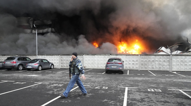 Ukrán katona megy egy orosz légicsapásban kigyulladt logisztikai centrum előtt Kijevben / Fotó: MTI/AP 