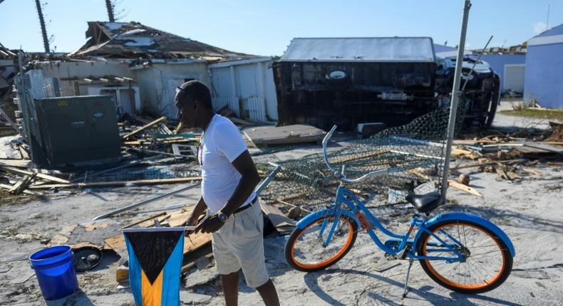 Irvin Russell carries the Bahamian flag as he walks past a damaged truck on Treasure Cay in the hurricane-hit Bahamas