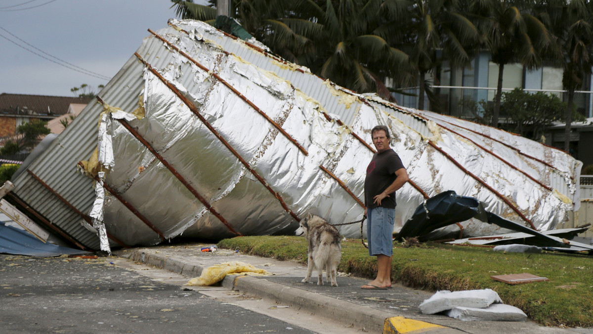 A resident from Sydney's southern suburb of Kurnell walks his dog past a house roof which had been blown down the street following a rare tornado