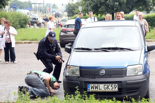 Policja przeszukuje samochod podczas alarmu bombowego.