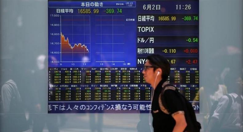 A man walks in front of a screen showing today's movements of Nikkei share average outside a brokerage in Tokyo, Japan, June 2, 2016. 
