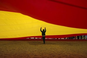 A child walks under a giant Spanish flag unfurled by supporters of Spain's Prime Minister Rajoy to s