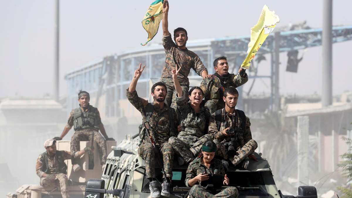 Syrian Democratic Forces (SDF) fighters ride atop of military vehicles as they celebrate victory in Raqqa