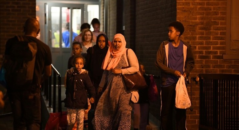 A family leave the Taplow Tower residential block on the Chalcots Estate in north London on June 23, 2017 as residents are evacuated because of fire safety concerns