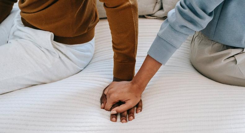 Couple holding hands on bed [Image: Alex Green]