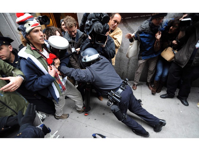 Policjant usiłujący usunąć z chodnika protestujących uczestników organizacji „Okupuj Wall Street”. Nowy Jork, USA, 2011