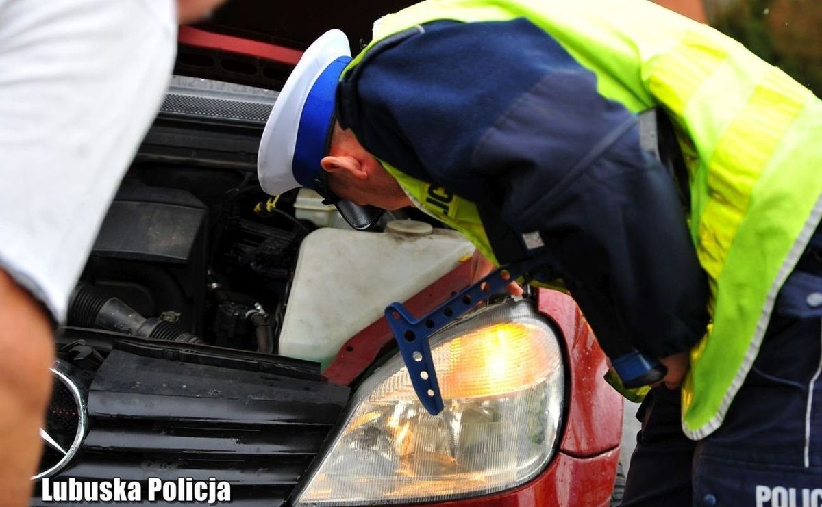 Policjant sprawdzający homologację reflektora z żarówką LED podczas kontroli drogowej w Polsce, kontrola oświetlenia samochodu