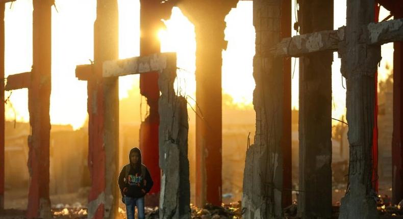 A Palestinian boy stands amidst the ruins of a building destroyed during the 50-day war between Israel and Hamas militants during the summer of 2014