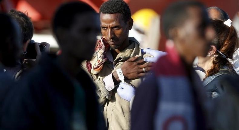 A member of police takes a picture of a migrant after disembarking from tug boat Asso29 in the Sicilian harbour of Pozzallo, southern Italy, May 4, 2015. REUTERS/Antonio Parrinello