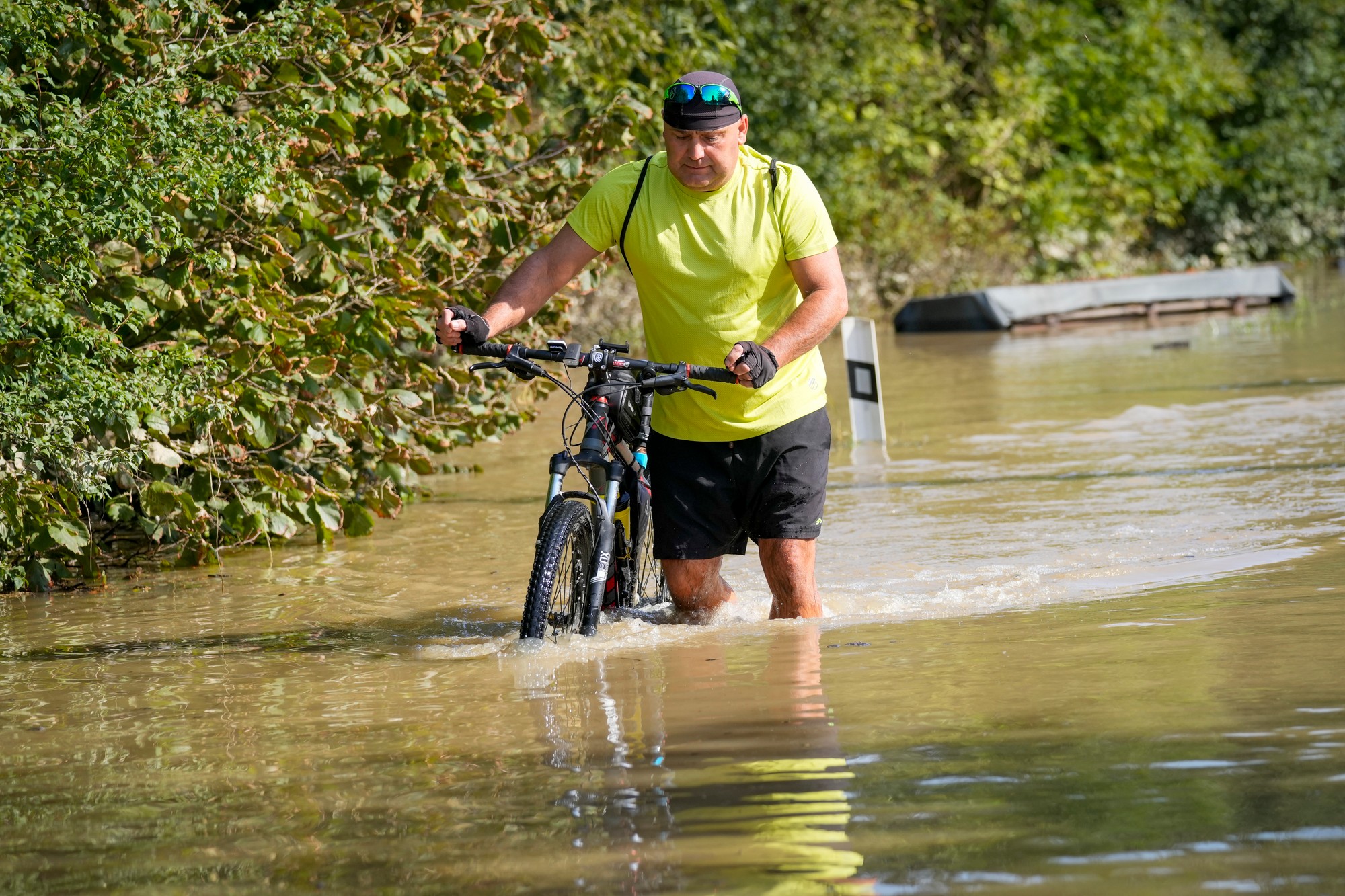 Obyvateľ tlačí bicykel cez zaplavenú ulicu v českom Bohumíne.