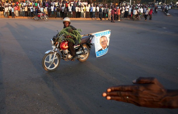 A supporter of opposition leader Kizza Besigye rides a motorbike in front of riot police in Kampala