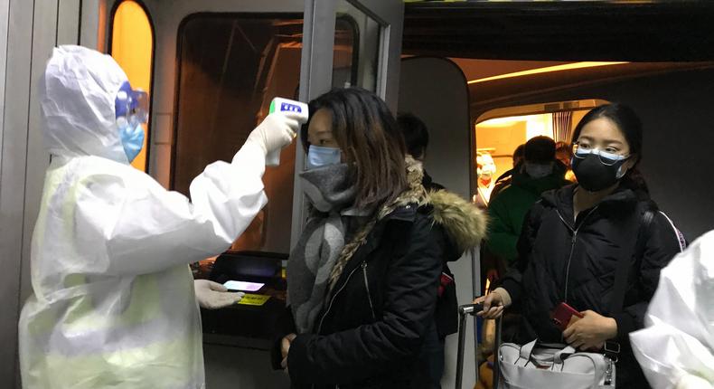 Health Officials in hazmat suits check body temperatures of passengers arriving from the city of Wuhan Wednesday, Jan. 22, 2020, at the airport in Beijing, China. Nearly two decades after the disastrously-handled SARS epidemic, China's more-open response to a new virus signals its growing confidence and a greater awareness of the pitfalls of censorship, even while the government is as authoritarian as ever. (AP Photo Emily Wang)