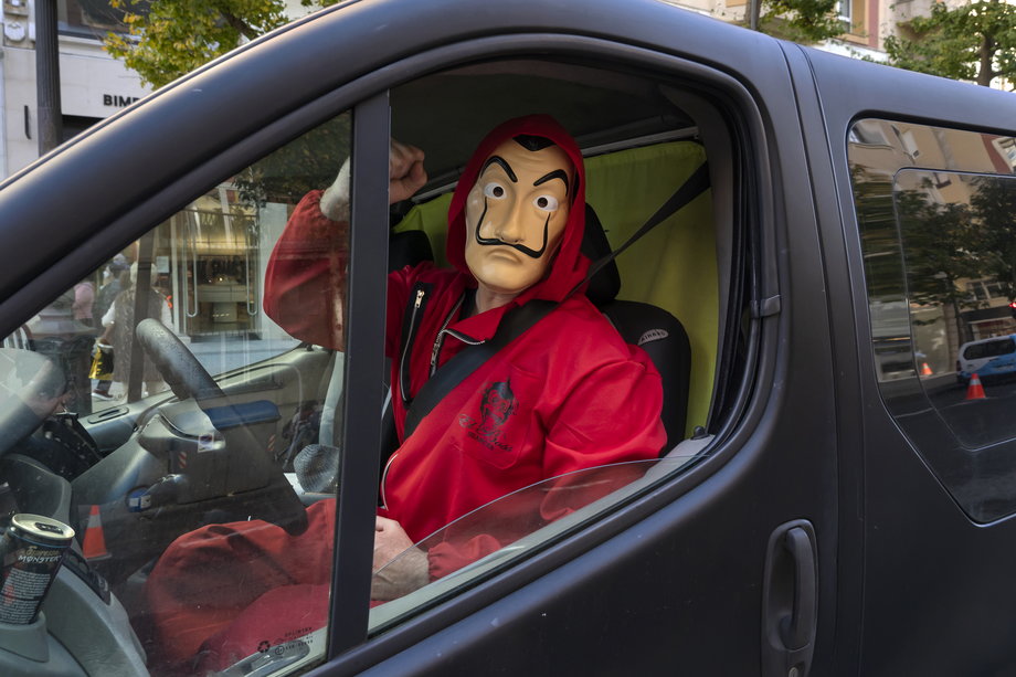 Postaci rabusiów z serialu "Dom z papieru" w charakterystycznych czerwonych kombinezonach i maskach bardzo szybko rozgościły się w popkulturze. Na zdjęciu: uczestnik protestu hotelarzy w hiszpańskim mieście Santander w listopadzie 2020 r.