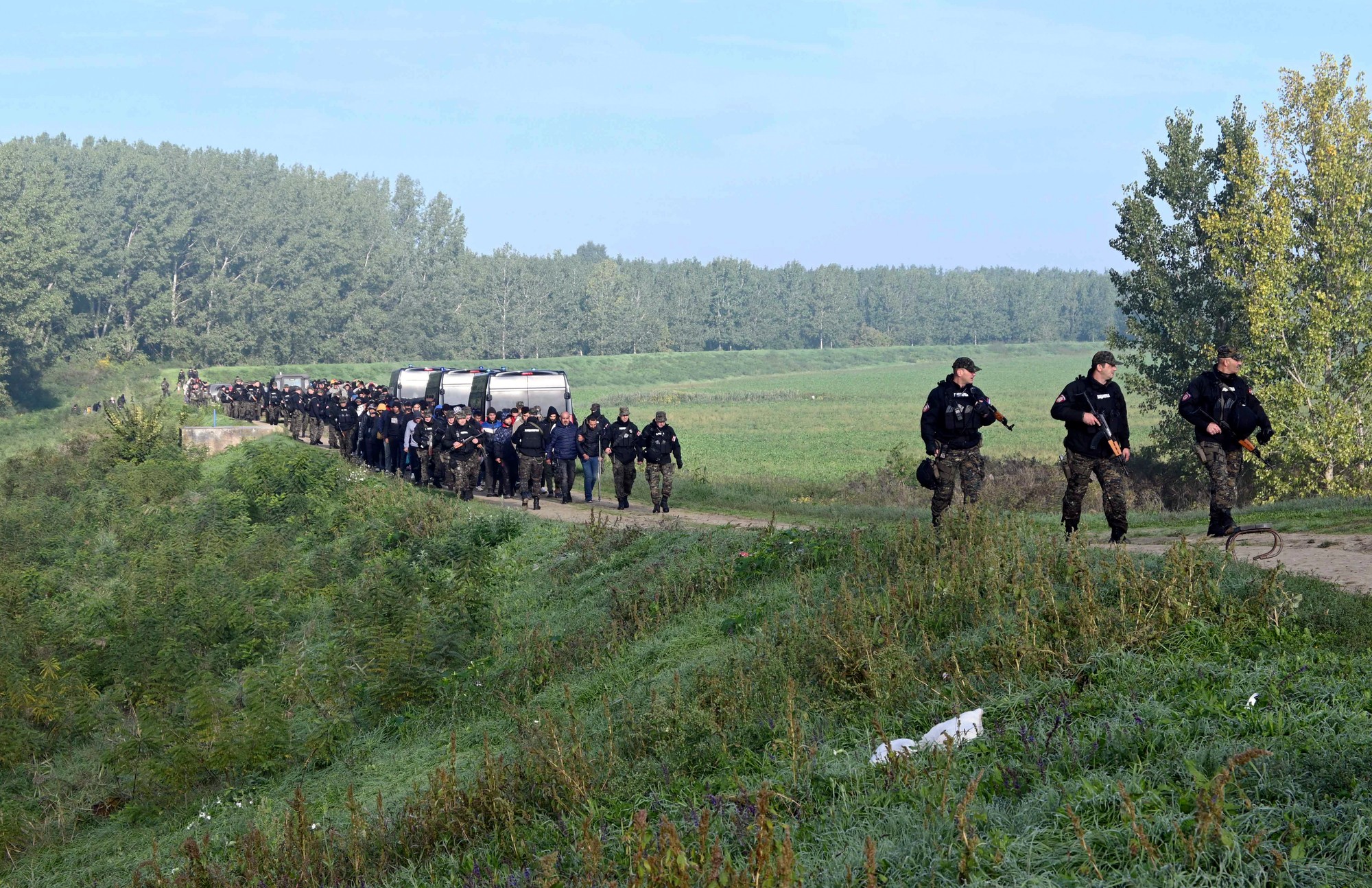 Srbskí policajti sprevádzajú migrantov pri obci Srpski Kustur.